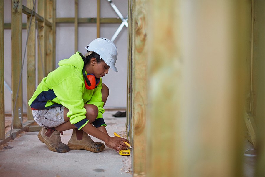 Female construction worker measuring home framing