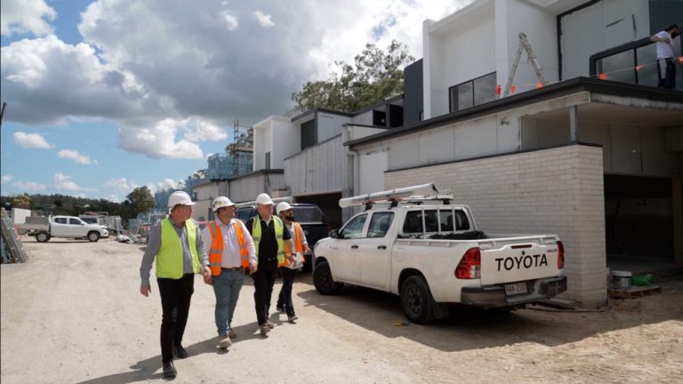 Four adults walking on home building site with PPE